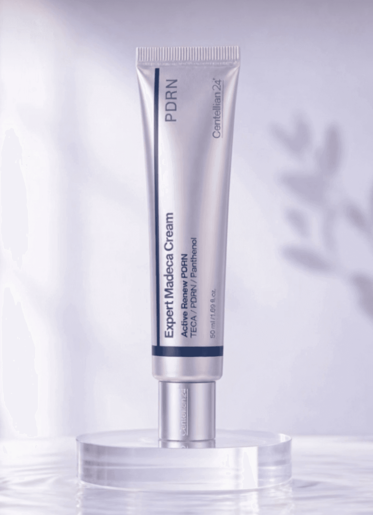 Centellian24 Expert Madeca Cream Active Renew PDRN tube on a clear acrylic riser in shallow water against a soft lavender backdrop