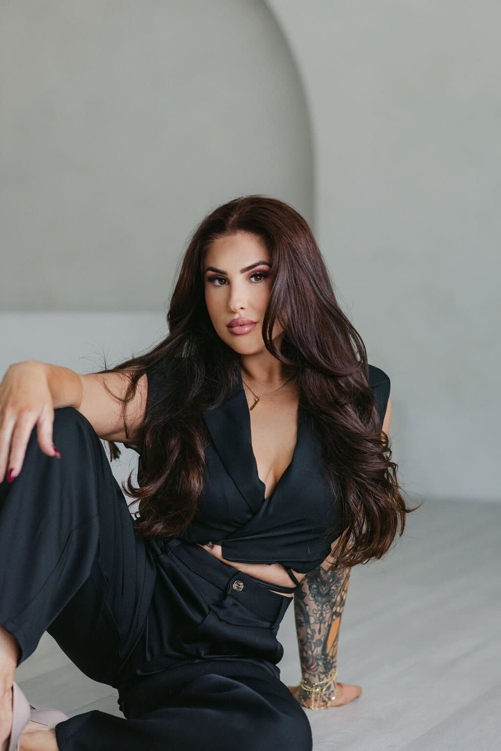 Meagan Greene photographed against a soft plaster wall in a black suit