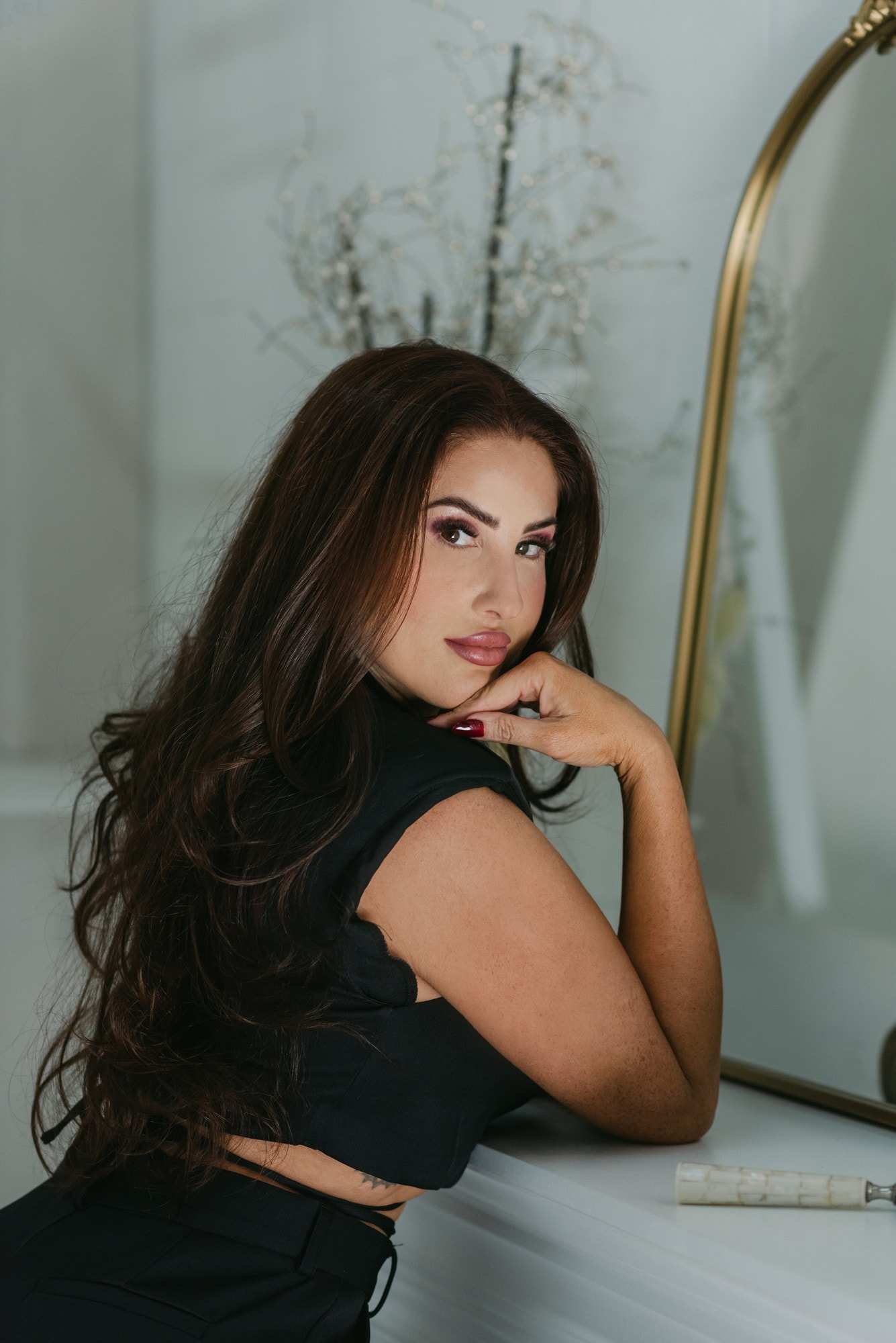 Meagan Greene resting her chin on her hand beside a gold mirror