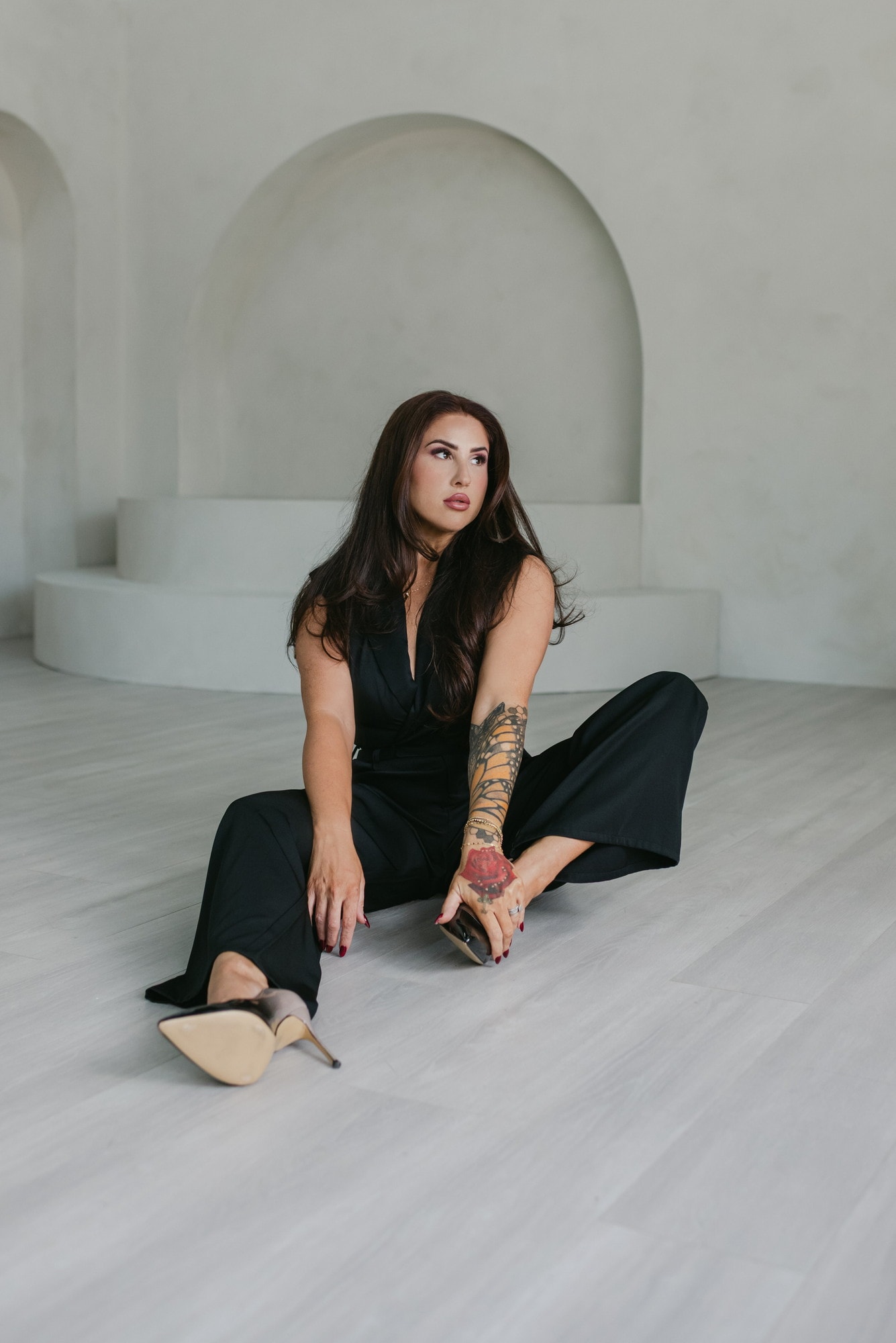 Meagan Greene seated on a studio floor in a black jumpsuit